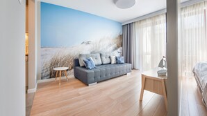 Een moderne slaapkamer met een grijze bank, een klein houten tafeltje en een bed.