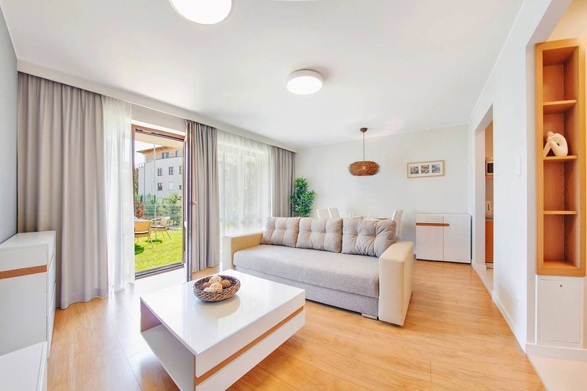 A modern living room with a sofa, a coffee table, and a wooden floor.