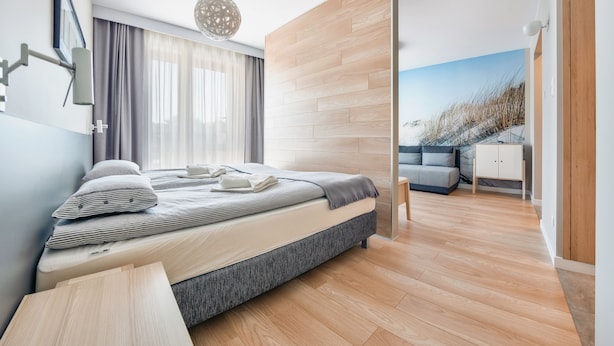 Een moderne slaapkamer met een bed, een nachtkastje, een lamp en uitzicht op een besneeerd landschap door een schuifdeur.