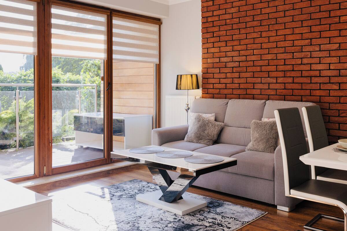 A modern living room with a grey sofa, a coffee table, and a dining area with a white table and chairs.