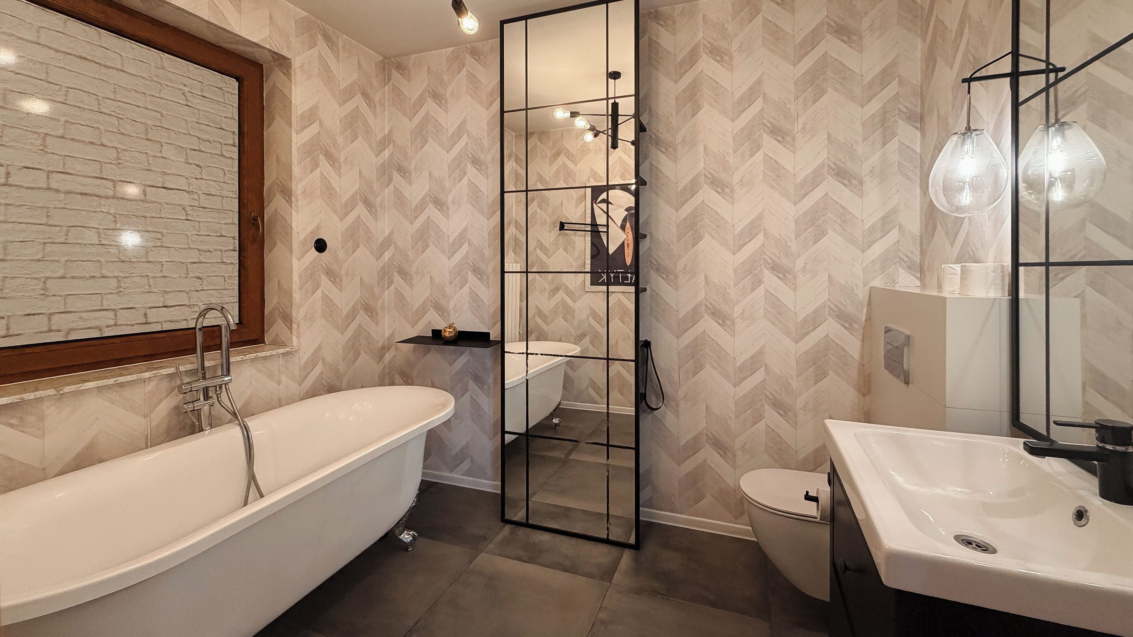 Une salle de bain moderne avec une baignoire sur pieds, une douche à parois de verre et un lavabo avec un miroir.