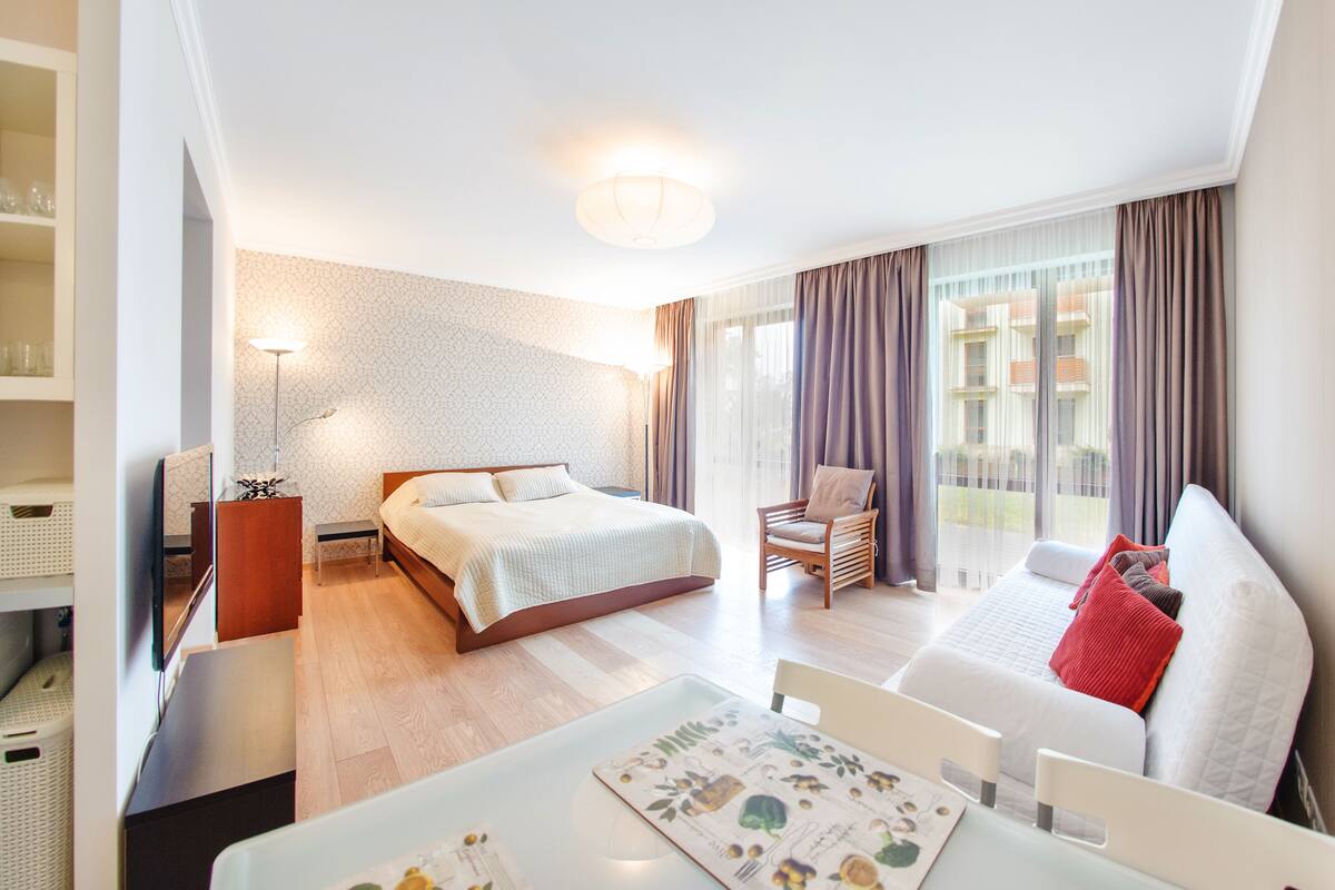A modern hotel room with a bed, a sofa, a desk, and a chair.