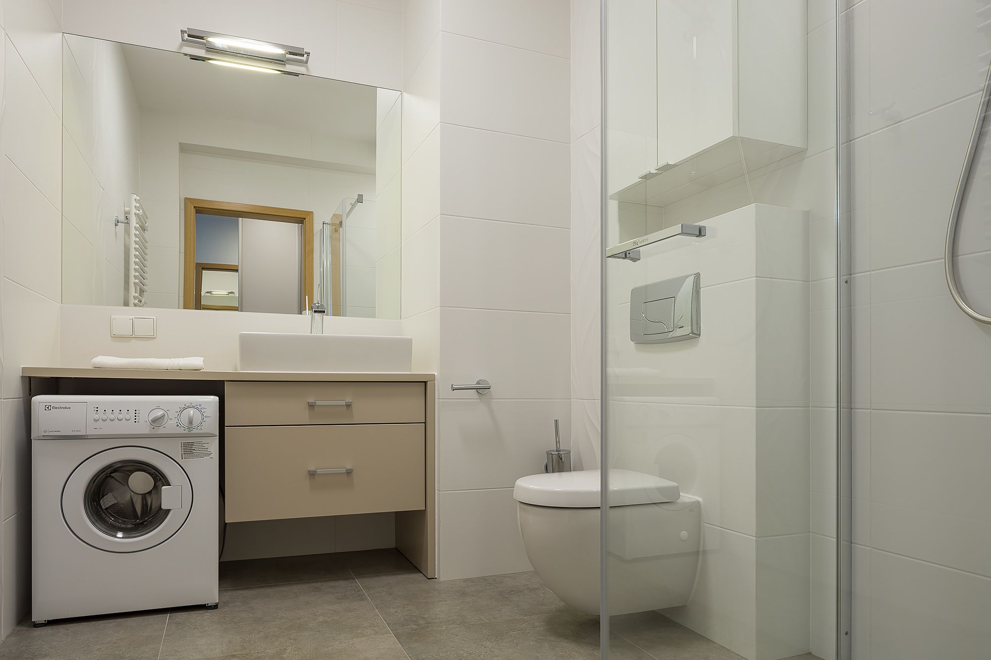 Un baño moderno con lavadora, inodoro y cabina de ducha de vidrio.