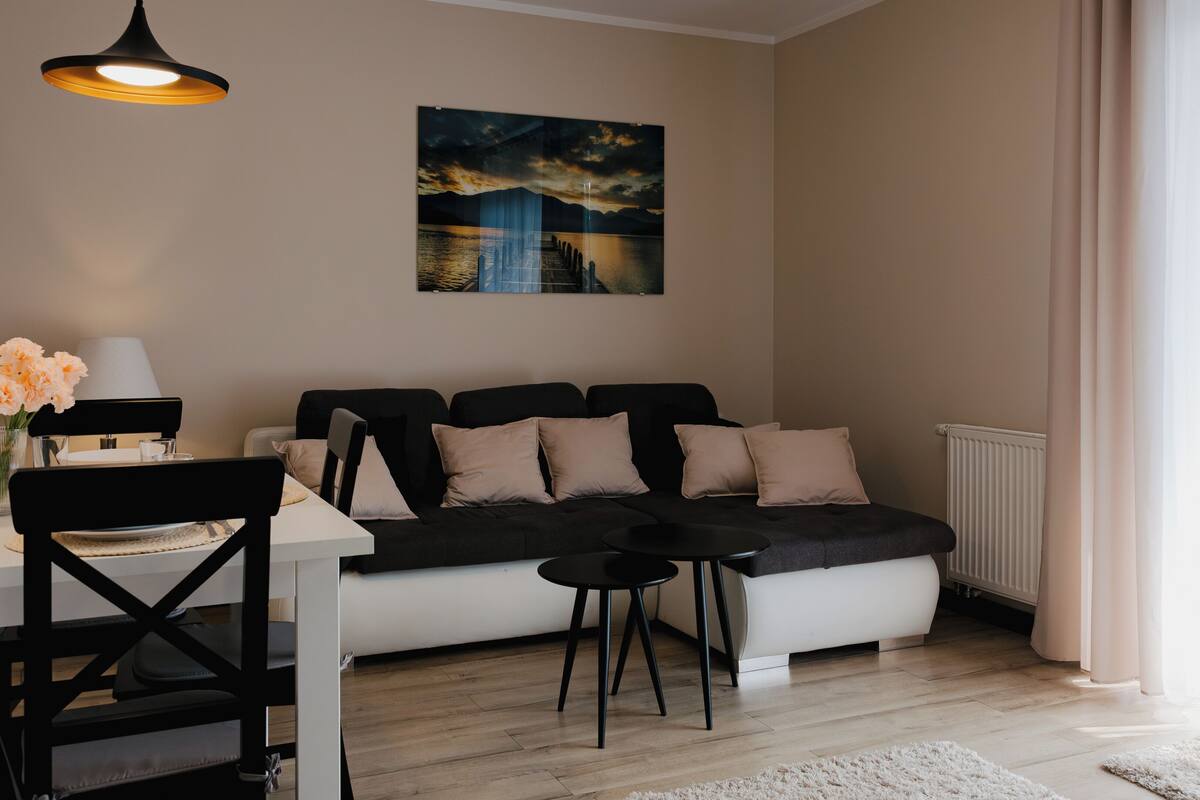 A modern living room with a sofa, a dining table, and a painting on the wall.