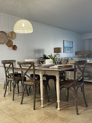 Un coin repas avec une table et des chaises en bois, un luminaire suspendu et un tableau accroché au mur.