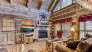 A rustic interior with a stone fireplace, wooden walls, and a large TV.