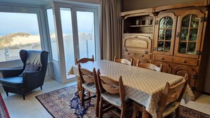 A dining area with a table set for six, surrounded by wooden chairs. A large wooden cabinet with glass doors is to the right. - Appartment with seaside view and 2 parking spaces (Oostduinkerke-Bad)