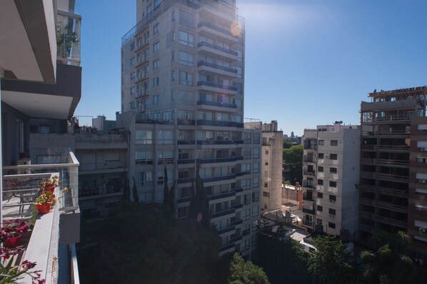 A high-rise building with multiple balconies, some with plants.