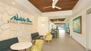 A modern interior with a stone wall, a seating area with a bench and chairs, a ceiling fan, and a framed picture on the wall. - Ocean & Sunset Views, FREE Parking & Washlet! (Honolulu)