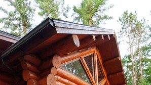 Une cabane en rondins avec une terrasse en bois, de grandes fenêtres et un drapeau américain.