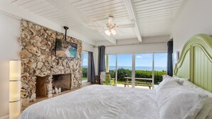 A bedroom with a stone fireplace, a large bed, and a view of the ocean. - Oceanfront 3-Bedroom / 2-Bath Luxury Townhouse in the heart of Melbourne Beach (Melbourne Beach)