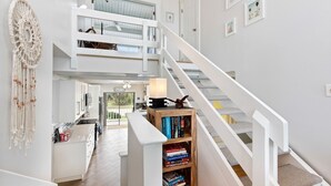 A spacious interior with a staircase, a bookshelf, and a dreamcatcher on the wall. - Oceanfront 3-Bedroom / 2-Bath Luxury Townhouse in the heart of Melbourne Beach (Melbourne Beach)