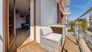 A balcony with wicker furniture, a view of the street, and a building with a balcony. - Apartamenty Sun & Snow Ustka Aquarius (Ustka)