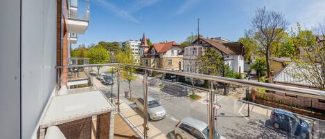 Un balcón con vista a una calle, coches aparcados y edificios residenciales.