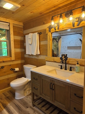 A wooden cabin bathroom with a toilet, sink, and wooden cabinets. - 3BR_3BA Log Cabin, Pond Front, Hot Tub, Pool Table, near Skiing & Pet friendly (Seven Devils)