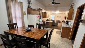 A spacious kitchen with a dining area, featuring wooden cabinets, a refrigerator, and a ceiling fan.