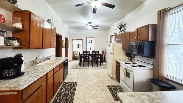 A kitchen with wooden cabinets, a microwave, stove, and a ceiling fan.