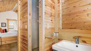 L’intérieur d’un chalet en bois comprend un lit, une salle de bain avec un lavabo et un espace douche.