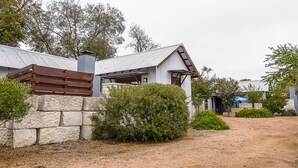 Un bâtiment rustique avec un mur en pierre, une clôture en bois et un toit en métal.