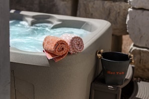 Un jacuzzi con una toalla enrollada y un cubo que dice 'Jacuzzi' a su lado.