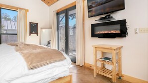 Une chambre à coucher avec un lit, une télévision, une cheminée et une table en bois.