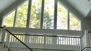 A staircase with white railings leading to a landing with large windows. - Beautiful new large family home inside gates of Country Club of Sapphire Valley. (Sapphire)
