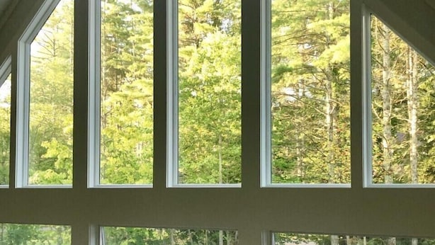 A room with large windows offering a view of a forested area. - Beautiful new large family home inside gates of Country Club of Sapphire Valley. (Sapphire)