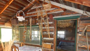 L’intérieur d’un chalet rustique, avec une table à manger en bois, des chaises et une grande fenêtre.