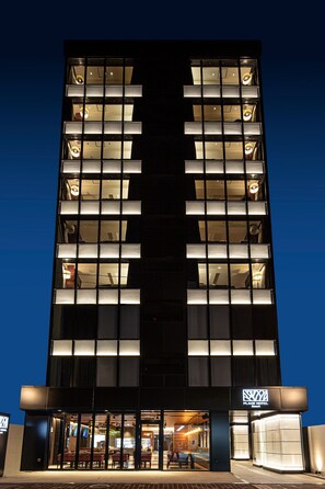 Een modern hotel met een symmetrische gevel, grote ramen en een goed verlichte entree.