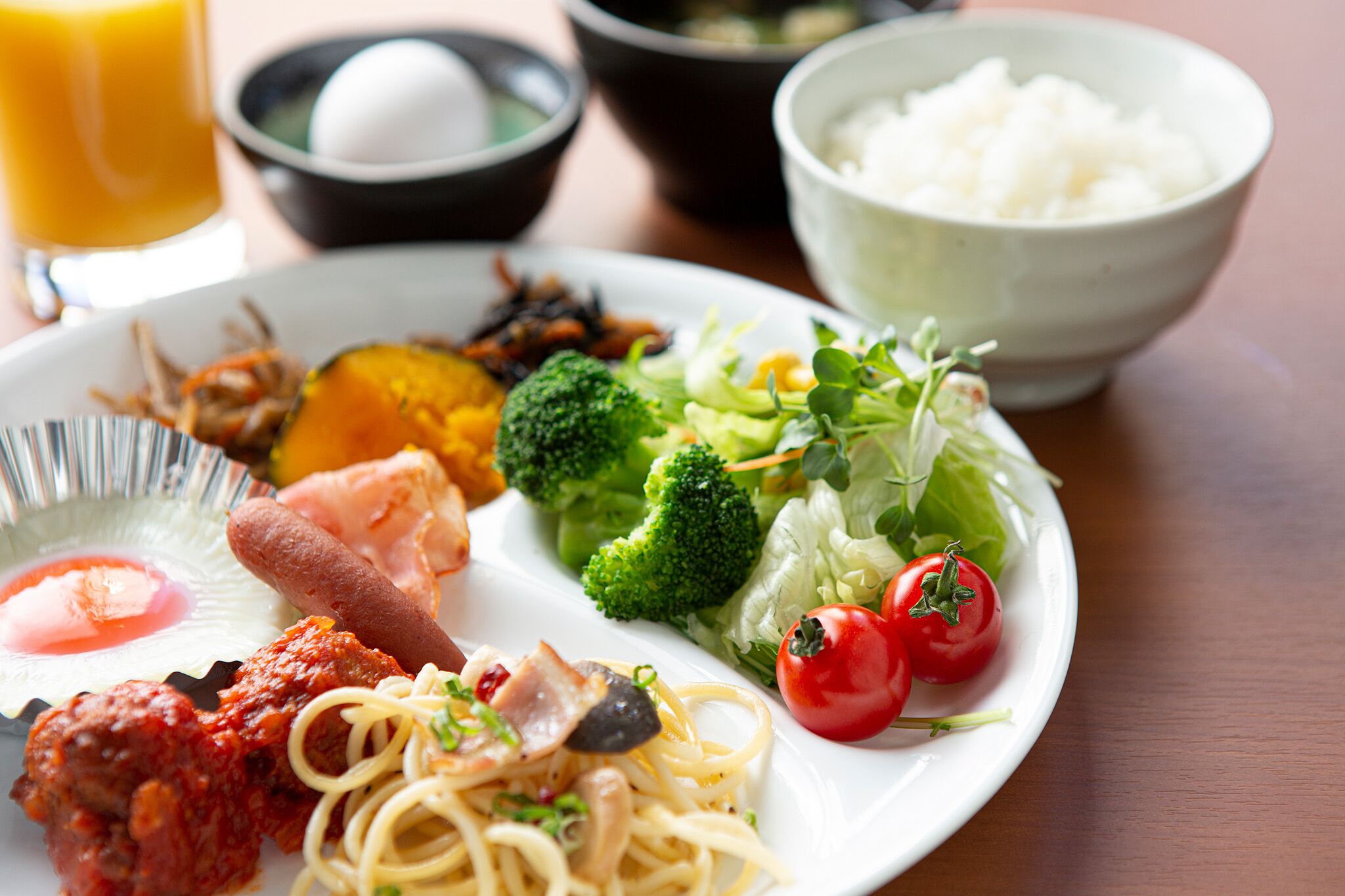 A plate of food with various dishes including noodles, vegetables, and meat.