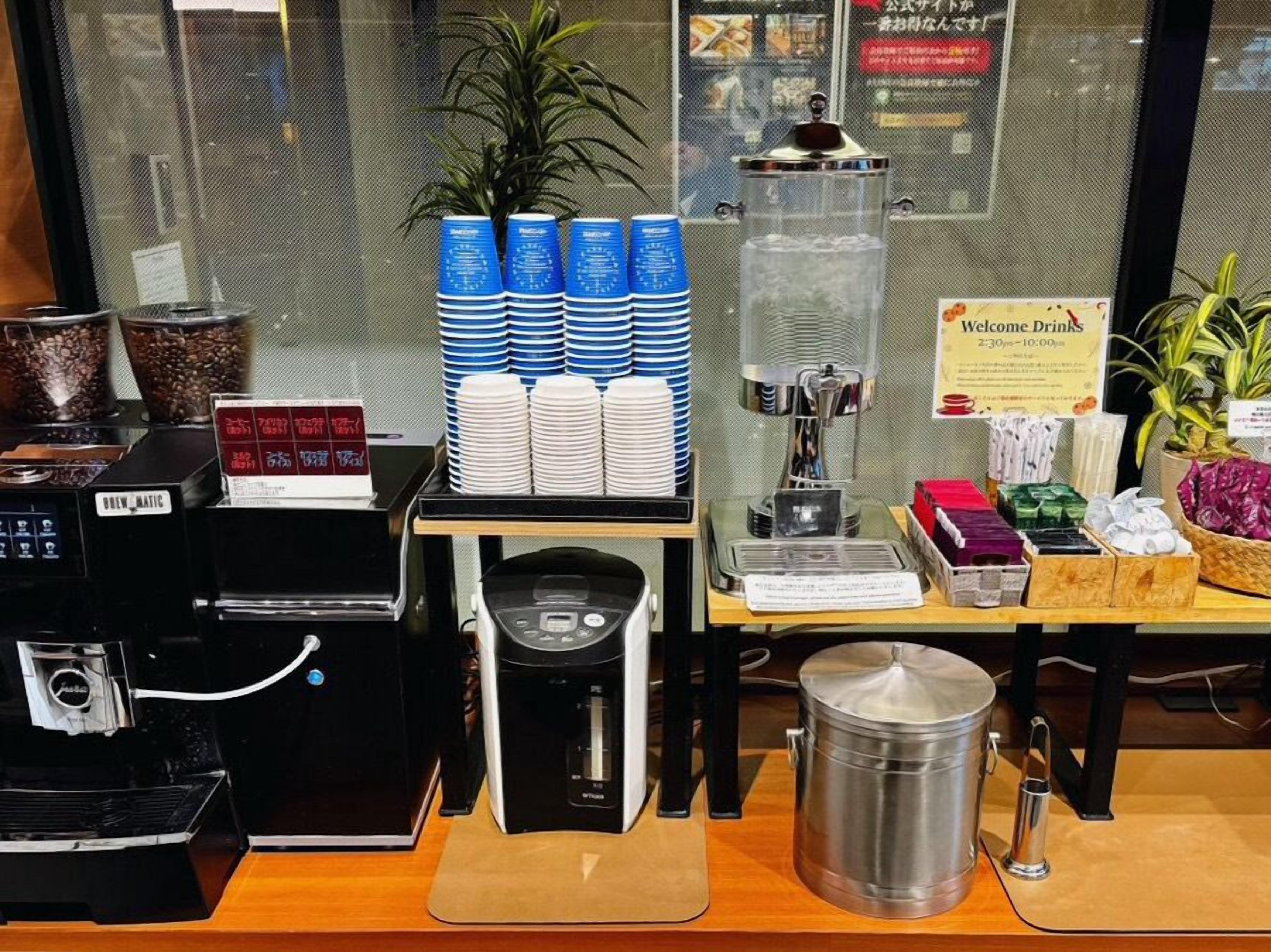 Una estación de café con varias máquinas de café, un molinillo y una variedad de cápsulas de café.
