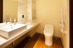 Un baño moderno con lavamanos, espejo y retrete blancos.