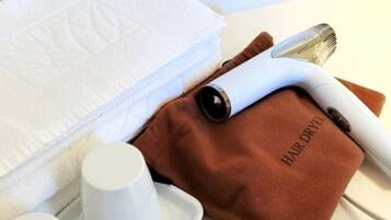 A bathroom with a towel, a hair dryer, and toiletries.