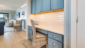 Een moderne keuken met blauwe kastjes, een rieten stoel en uitzicht op de woonkamer.