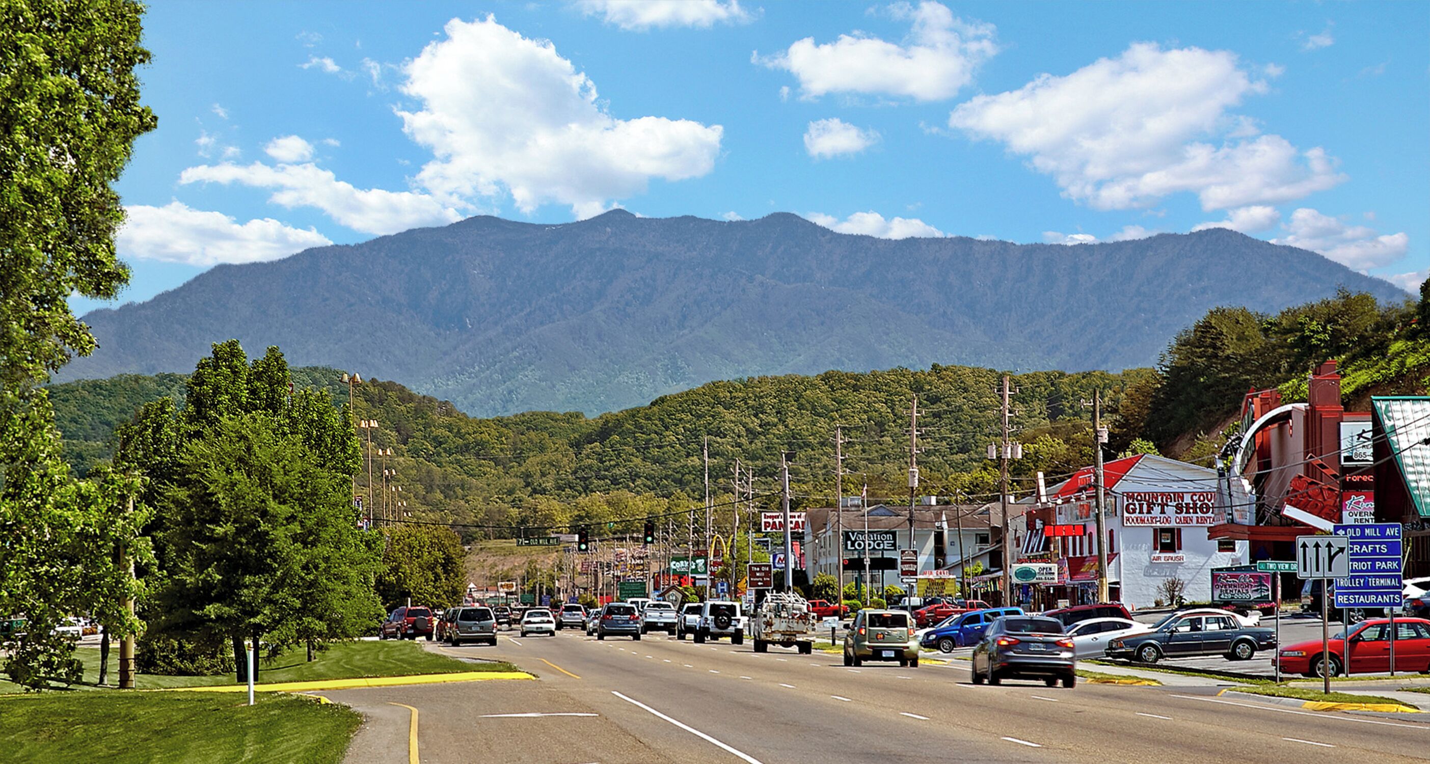 A town street with shops and a mountain backdrop.