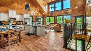Eine geräumige Küche mit Holzausbau, einer zentralen Kochinsel und einem Essbereich mit Tisch und Stühlen.