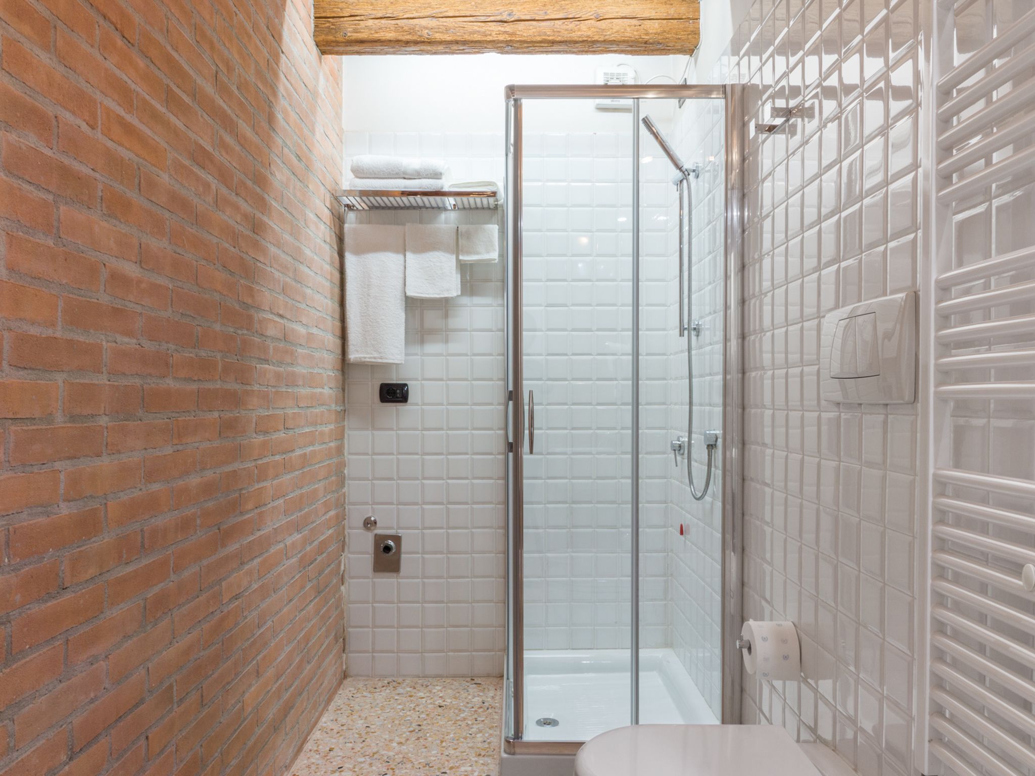 A bathroom with a glass shower enclosure, a white bathtub, and a toilet.