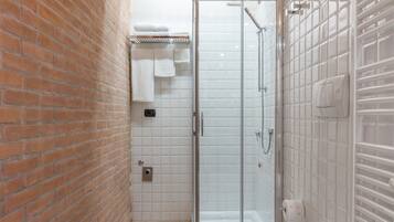 A bathroom with a glass shower enclosure, a white bathtub, and a toilet.