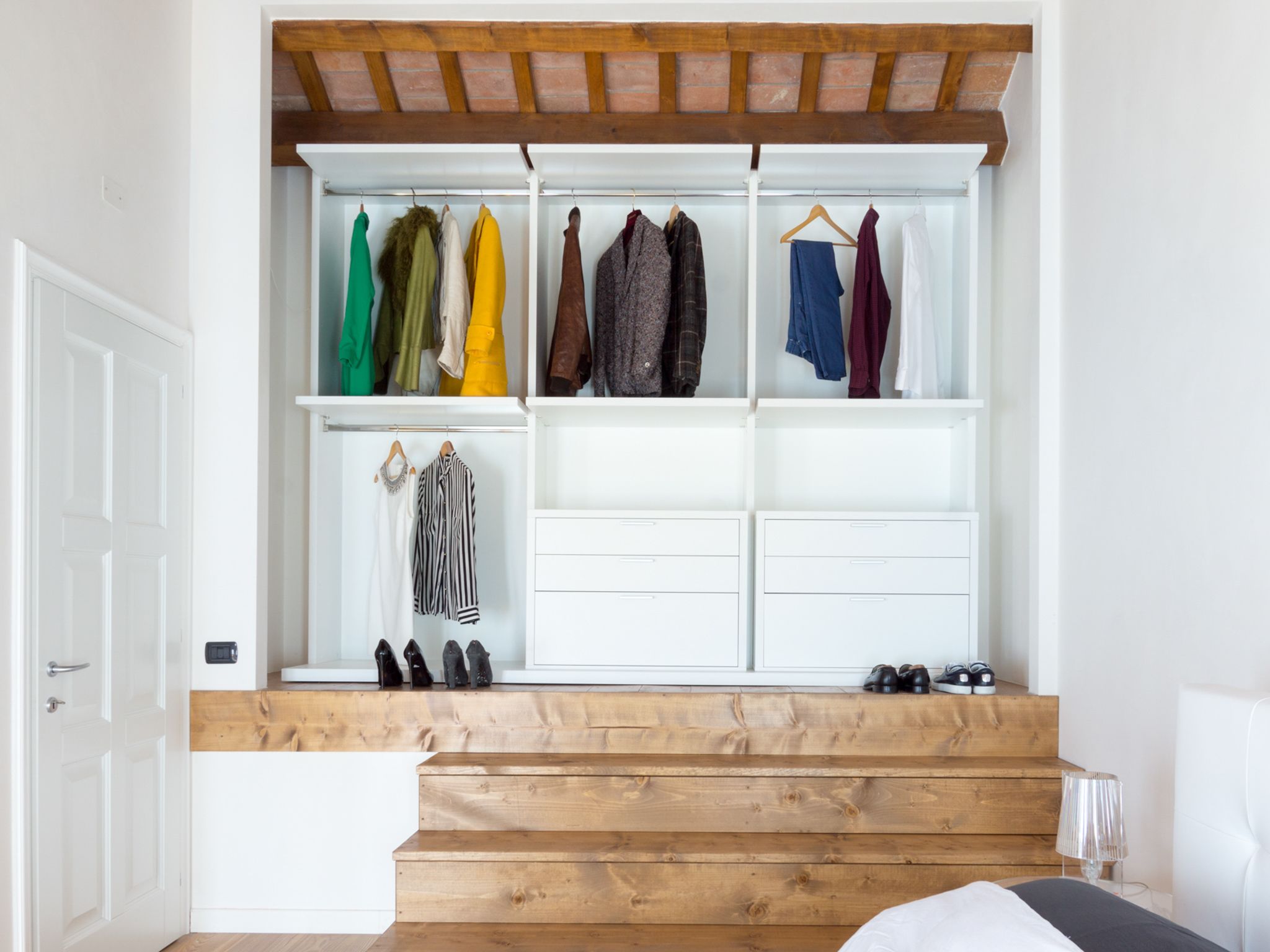 A bedroom with a built-in wardrobe, wooden staircase, and a bed.