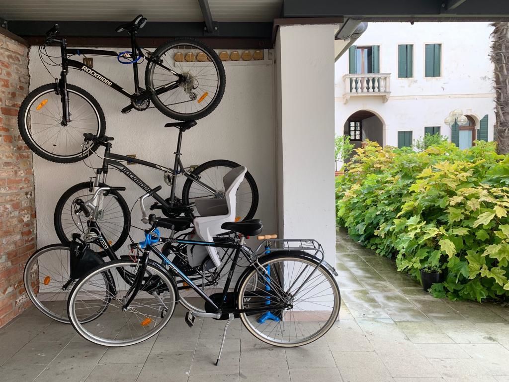 A bicycle parked in a covered area with a brick wall and a white building in the background.