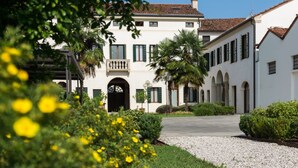 A white building with a tiled roof, arched windows, and a central entrance. - Residence Le Bugne (Noale)
