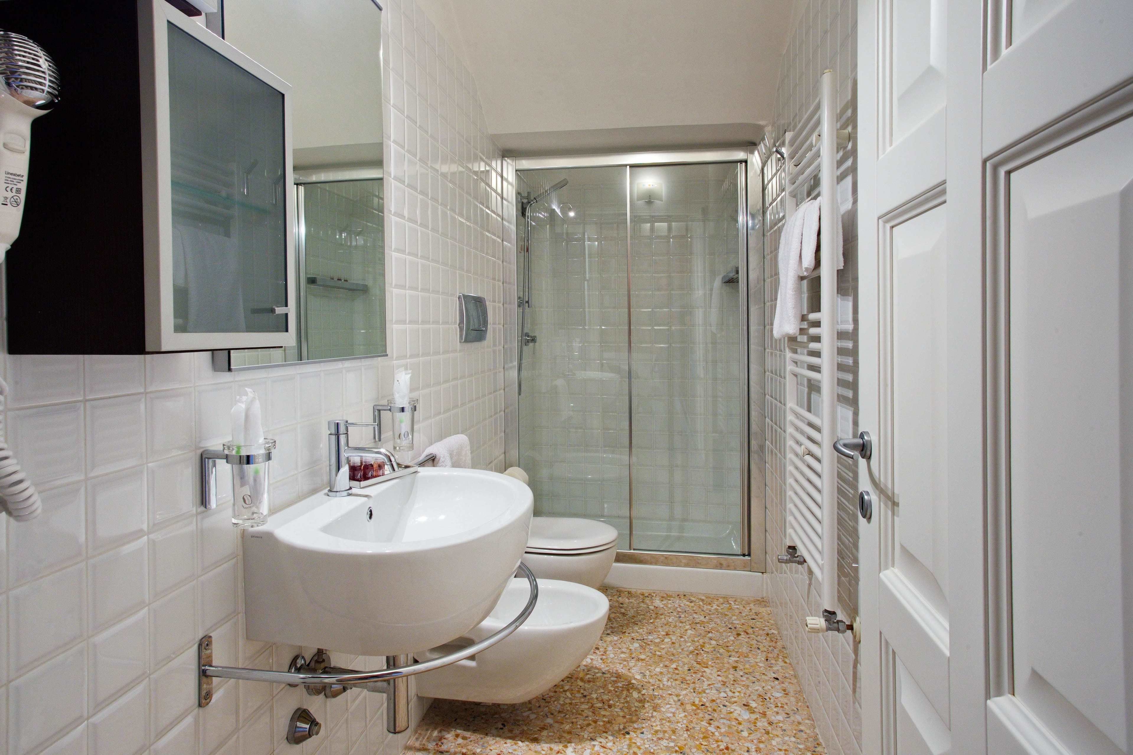 A bathroom with a white sink, a mirror, a toilet, and a glass-enclosed shower.