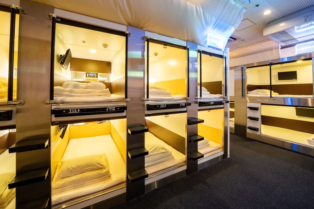 A row of bunk beds in a hotel room with a control panel and a television.
