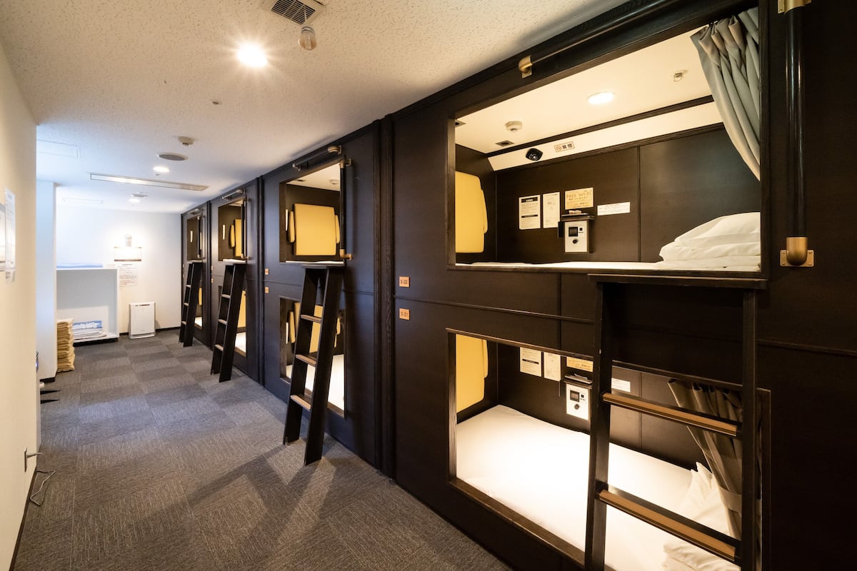 A hotel room with bunk beds, a desk, and a small window.