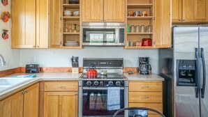 Una cocina con armarios de madera, estufa de acero inoxidable, microondas y refrigerador.