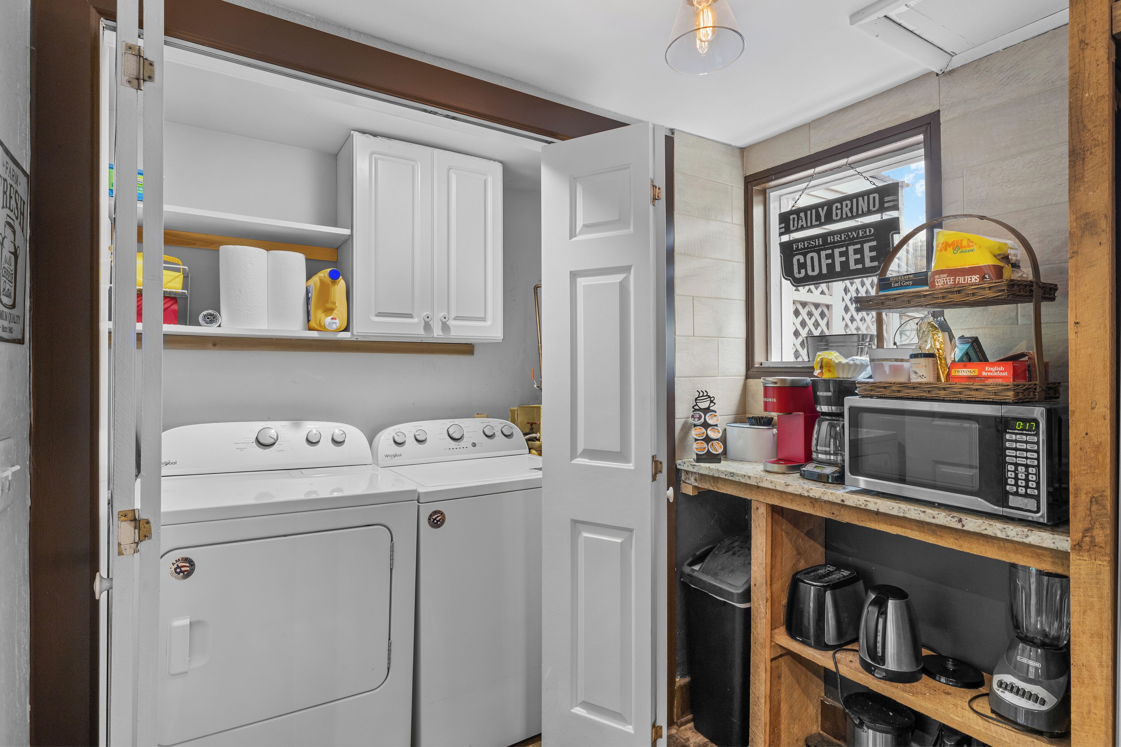 A compact kitchen with a washing machine, a coffee machine, and a microwave on the countertop.