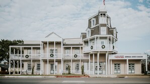 A historic building with multiple balconies, a tower, and a sign for the National Museum of the Pacific War Admiral Nimitz Gallery.