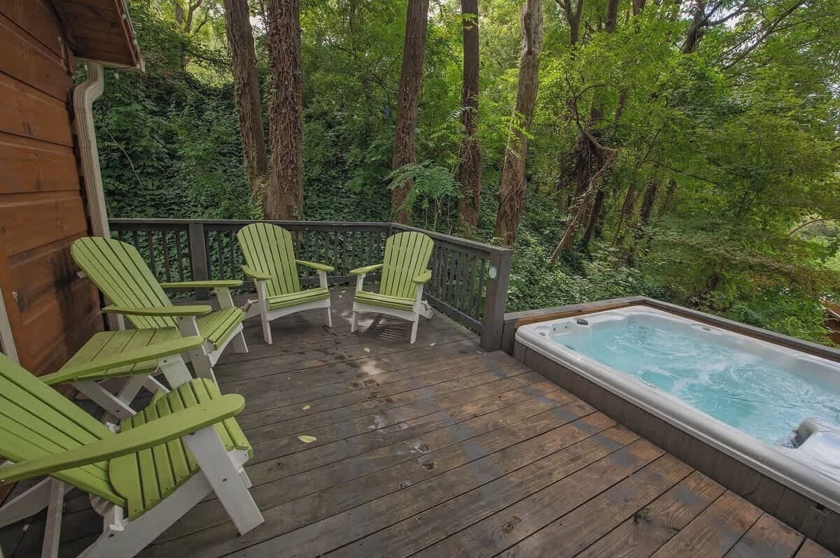 A wooden deck with three Adirondack chairs and a hot tub.