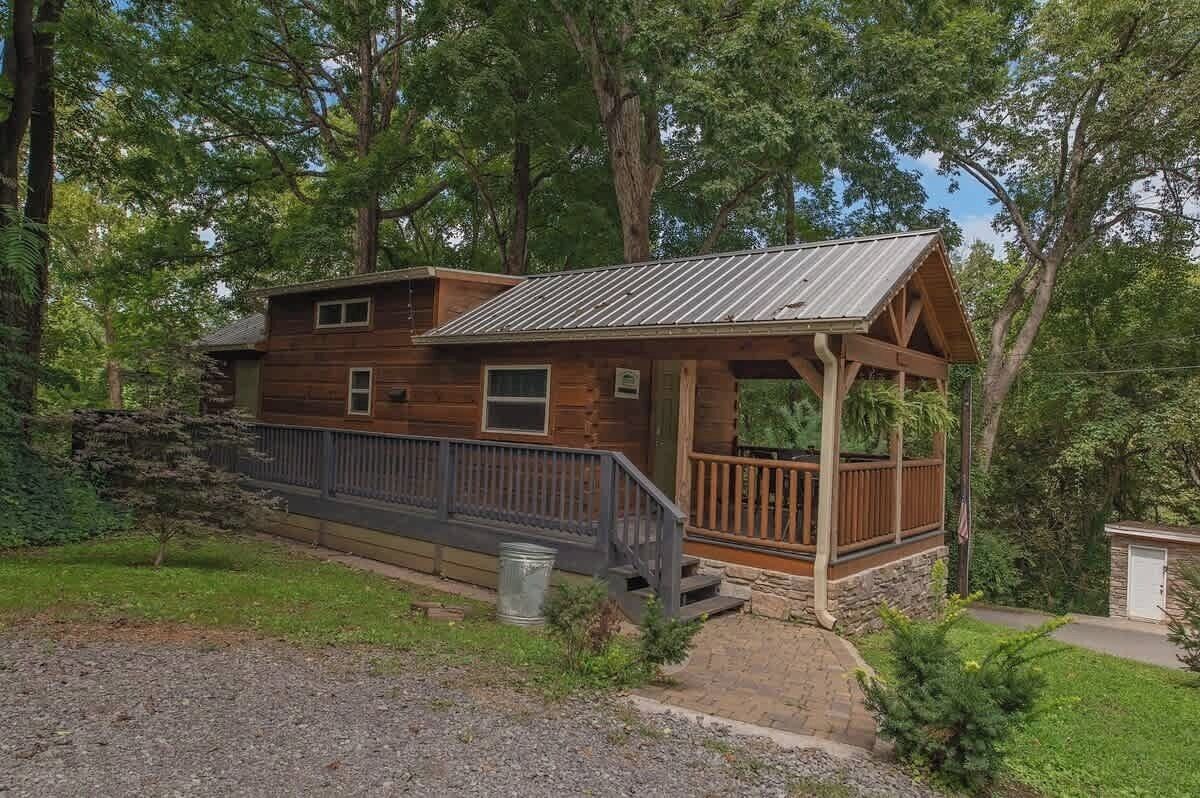 Une cabane en bois dotée d’un porche, d’un petit abri attenant et de fondations en pierre.