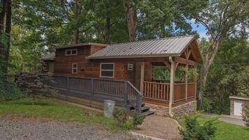 Une cabane en bois dotée d’un porche, d’un petit abri attenant et de fondations en pierre.